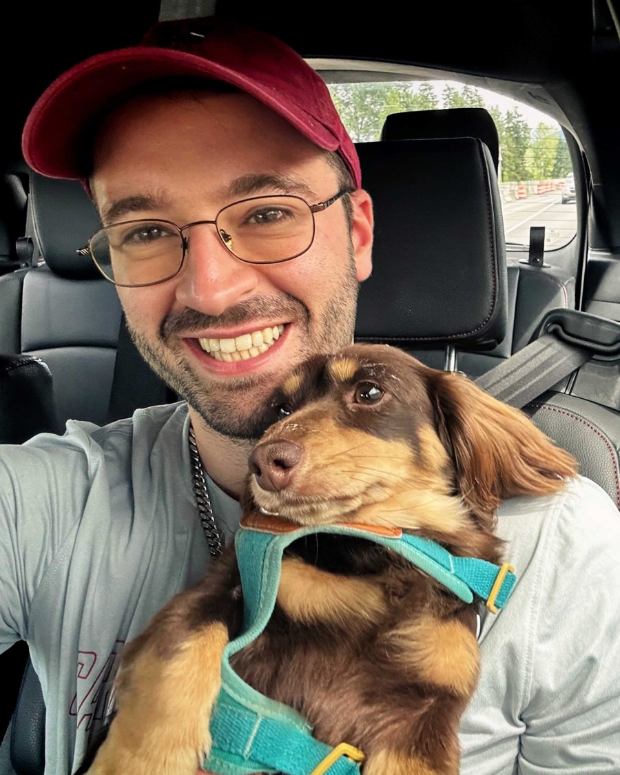 Alexander Shypula holding a long-haired dachshund in a car